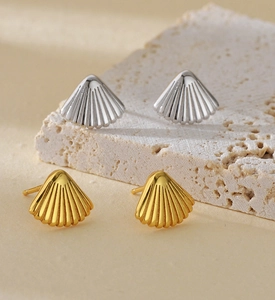 Detailed macro view of fan-shaped shell stud earrings in gold and silver finishes