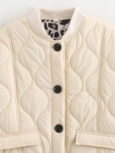 Detail of quilted beige jacket featuring ribbed collar and leopard print lining accents