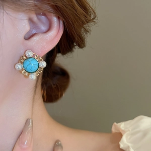 Detail of vintage earring with turquoise stone and pearls on golden filigree frame