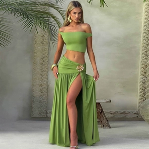 Detail of grass green crop top and high slit maxi skirt with metal flower decoration