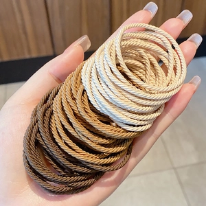 Élastiques à cheveux tissés tons terre, tenus en main pour les détails de texture