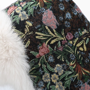 Dettaglio del tessuto jacquard floreale e della morbida pelliccia bianca sul colbacco
