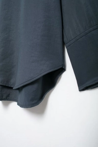 Detailaufnahme von Saum und Nähten einer dunkelblauen Bluse im Morandi-Stil