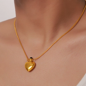 Minimalist gold heart bottle pendant necklace with sleek snake chain on female neck