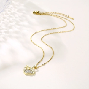 Collier cœur doré avec détail de nœud et zircons étincelants sur fond blanc