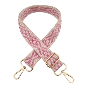 Detail of bohemian pink and beige geometric woven bag strap with gold metal buckles