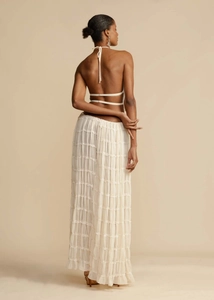 Back view of a white halter neck backless top paired with a tiered ruffle maxi skirt