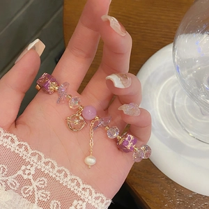 Detail of beaded bracelet with purple amethyst stones and gold planet charm on wrist