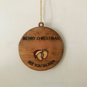 Detail of wooden Christmas ornament with baby footprints and See You In 2024 text