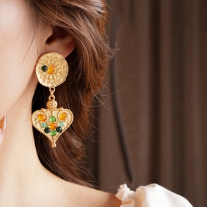 Close-up of vintage golden fringe earrings with colorful gemstones worn by a model