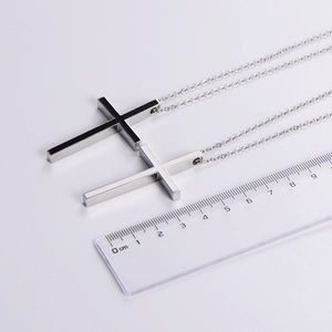 Detail showing two silver stainless steel cross pendants with ruler for size scale