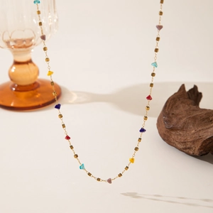 Detail of colorful heart charm necklace with gold beads on a wooden and glass display