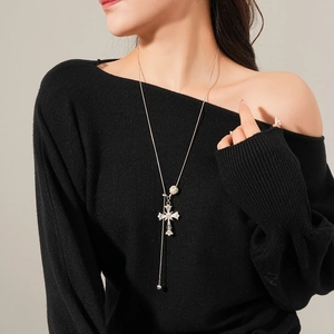 Detail of silver long necklace featuring a cross pendant with tiger eye stone inlay