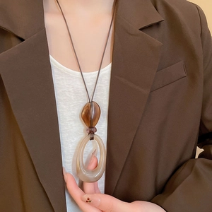 Detail of vintage resin double pendant necklace worn over a coffee-colored blazer