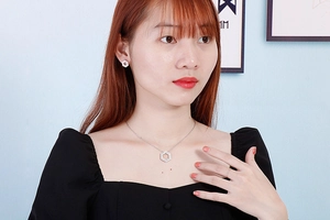 Close-up of a silver hexagonal honeycomb necklace and stud earrings worn by a model