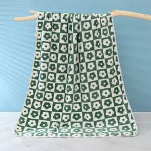 Detail of forest green checkered towel with small floral patterns on wooden branch