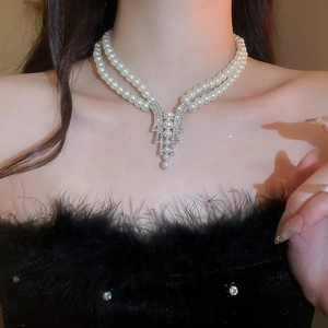 Detail of elegant double-layer pearl necklace with diamond pendant worn on a model