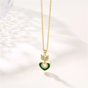 Golden necklace with green heart pendant and crystal-studded arrow in minimalist style