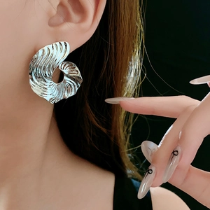 Macro shot of silver swirling striped earrings with metallic ripples on a model's ear