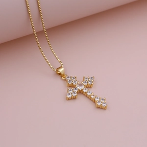 Macro shot of gold cross pendant necklace featuring full white zircon pave and box chain