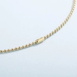 Macro detail of gold-plated bead chain connector and polished metal clasp finish