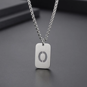 Vue macro du pendentif lettre O argenté avec texture métal brossé et chaîne blé