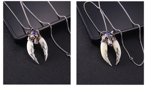 Detailed shot of a stainless steel wolf head pendant with red eyes and faux wolf tusks
