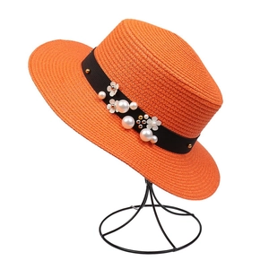 Detail of orange straw boater hat with black ribbon, white flowers and pearl accents