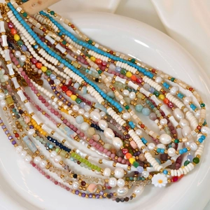 Colorful beaded necklace with freshwater pearls and daisies in a white ceramic tray