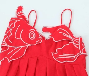 Gros plan d'une robe rouge à bretelles avec une grande broderie de carpe koï