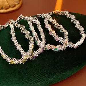 Luxurious multi-color gemstone tennis bracelets set in silver settings on a velvet stand