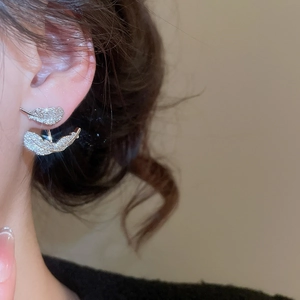Detail of silver feather stud earrings with cubic zirconia worn on a model's ear