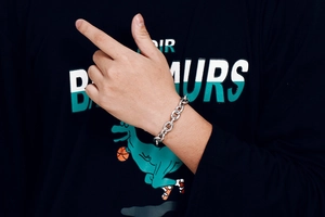 Close-up of a silver stainless steel chunky link bracelet worn on a model wrist
