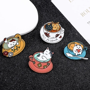 Macro detail of cat and rabbit enamel coffee cup pins on black textured background