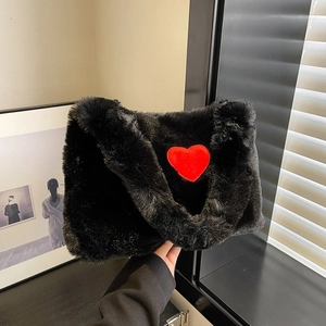 Detail of black faux fur tote bag featuring a vibrant red plush heart patch design