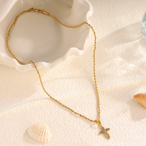 Macro view of gold cross pendant with pavé rhinestones on a twisted rope chain necklace