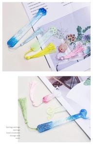 Detail of glitter resin bookmarks in cat paw and dolphin shapes with silk tassels