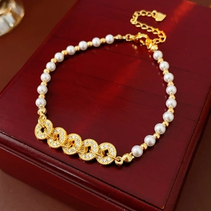 Macro shot of gold pearl bracelet with zircon rings on a dark red luxury wooden jewelry box