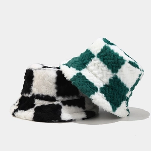 Detailed close-up of thick plush bucket hats in black-white and green-white plaid patterns