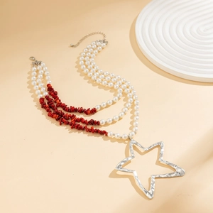 Detail of layered necklace with white pearls, red stone beads, and silver star pendant