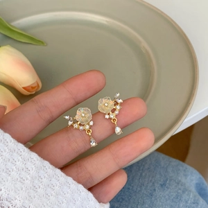 Handheld shot of floral cluster drop earrings with frosted petals and crystals