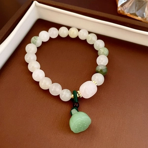 Detail of beaded bracelet featuring jade beads and a green lotus seedpod pendant