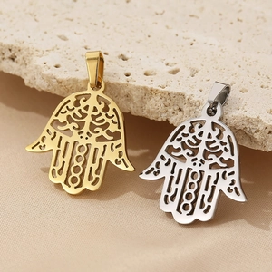 Detailed macro of gold and silver hollow Hamsa Hand pendants on natural stone