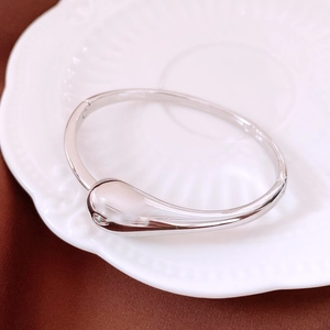 Detailed macro view of silver water drop bracelet with zircon on white embossed ceramic plate