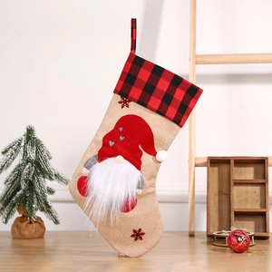 Linen Christmas stocking with red plaid and gnome design on a festive wooden background