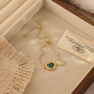 Detail of adjustable gold box chain bracelet with heart abalone shell pendant and luxury finish