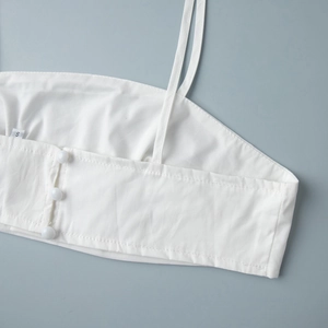 Détail de caraco en coton blanc avec trois boutons en résine et étiquette taille S