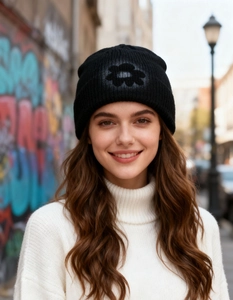 Detail of a black knitted beanie with flower pattern worn outdoors in autumn winter style