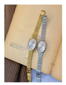 Retro oval dial quartz watches with gold and silver metal link bands on vintage paper