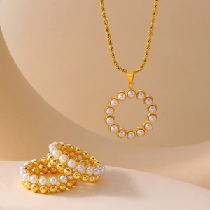 Elegant gold jewelry set with multi-layer pearl necklace and matching rings on soft background